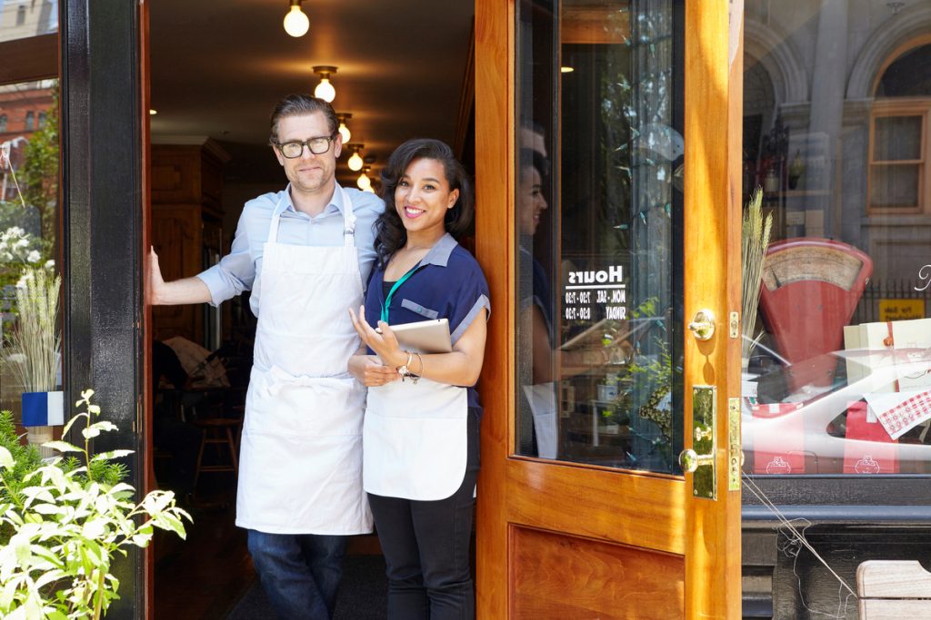 Portrait of male and female workers in bakery, standing in doorway